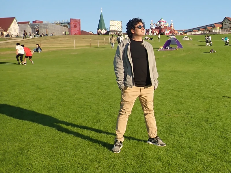 Wide portrait of Dr. Ram C. Sharma wearing sunglasses in an open green park.