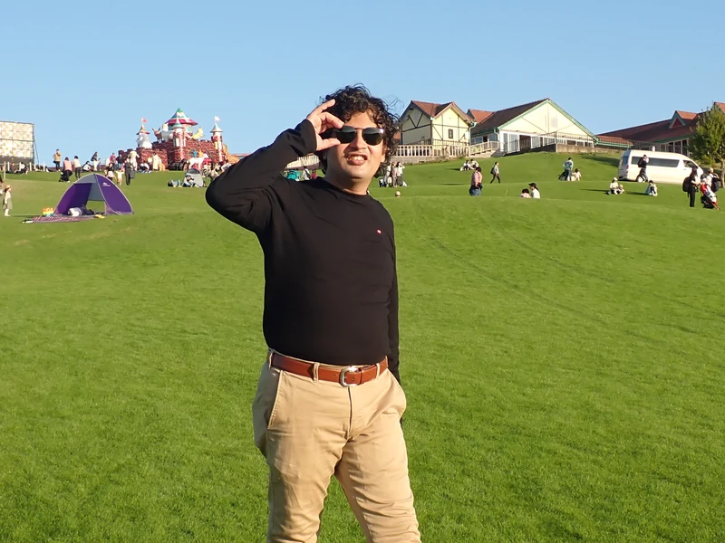 Dr. Ram C. Sharma wearing sunglasses in a sunny park landscape.