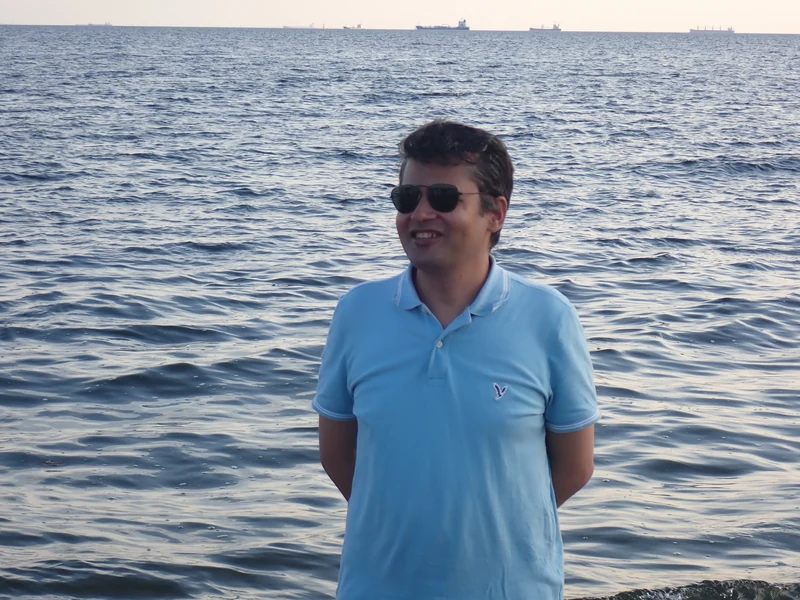 Dr. Ram C. Sharma wearing sunglasses by a calm waterfront.