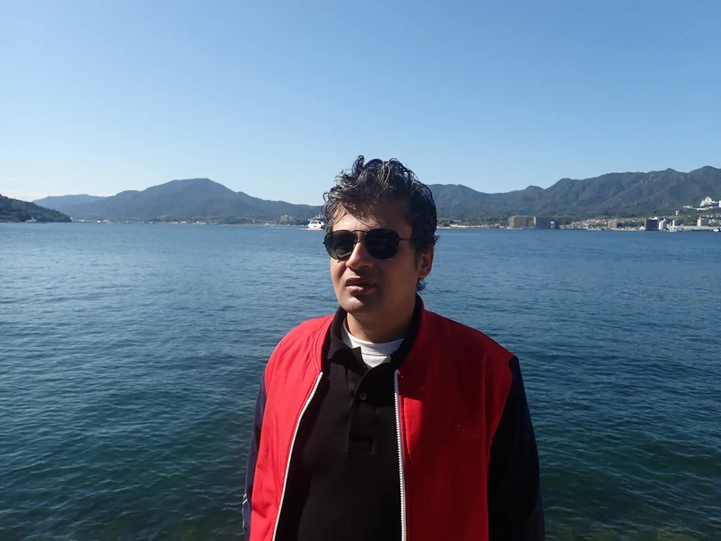 Dr. Ram C. Sharma wearing sunglasses in front of a mountain lake.